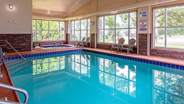 Una piscina interior con ventanales, sillas y un letrero de salvavidas.