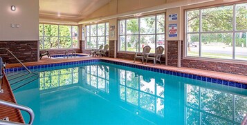 Una piscina interior con ventanales, sillas y un letrero de salvavidas.