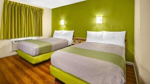 Habitación de hotel con dos camas, paredes verdes y suelo de madera.