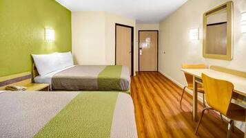 A hotel room with a bed, a desk, and a chair. There are two doors, one leading to the bathroom and another to the hallway.