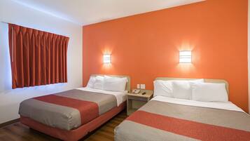 A hotel room with two beds, orange walls, and bedside lamps.