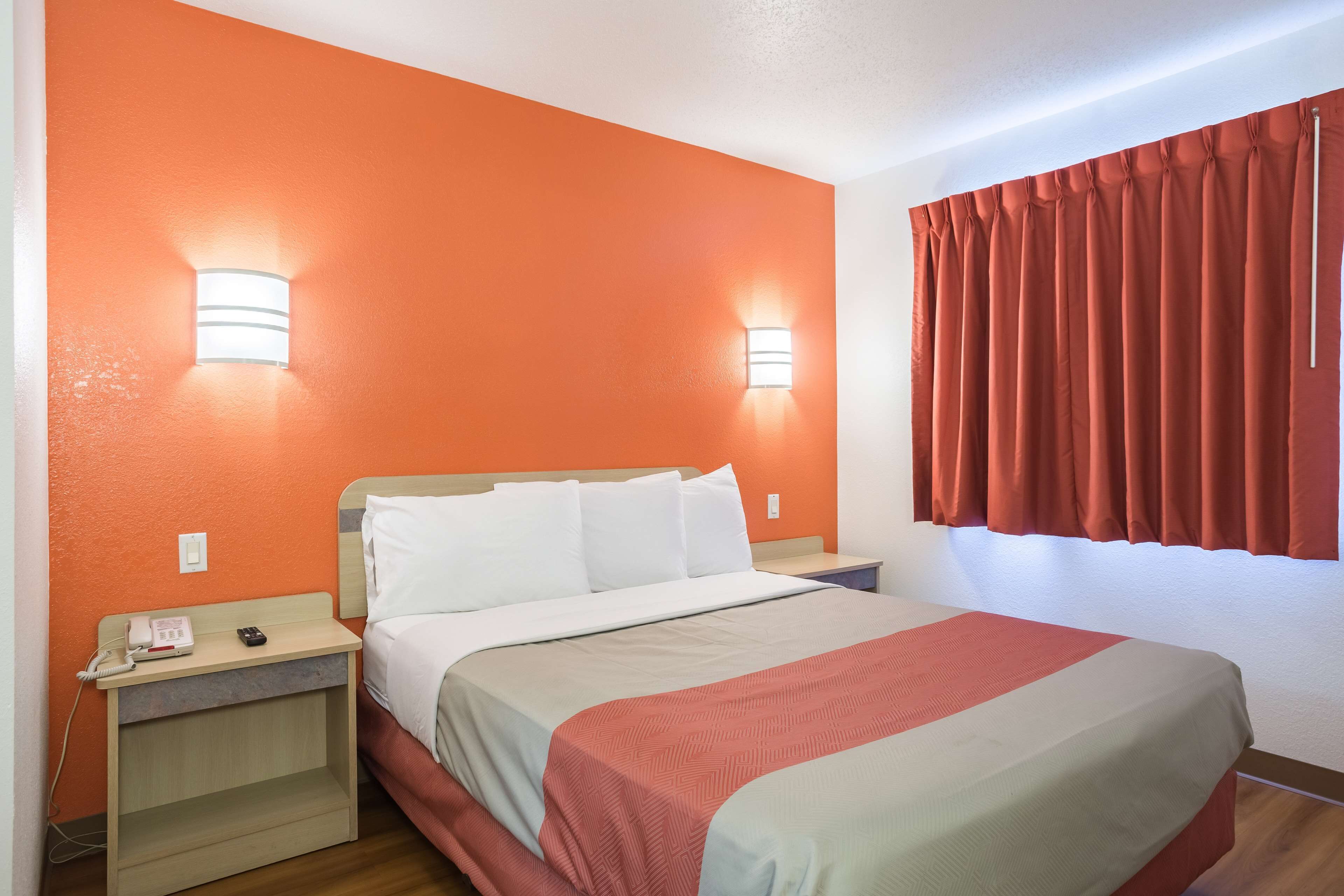 Habitación de hotel con cama, dos mesitas de noche, un teléfono y una ventana con cortinas.