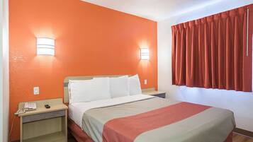 Habitación de hotel con cama, dos mesitas de noche, un teléfono y una ventana con cortinas.