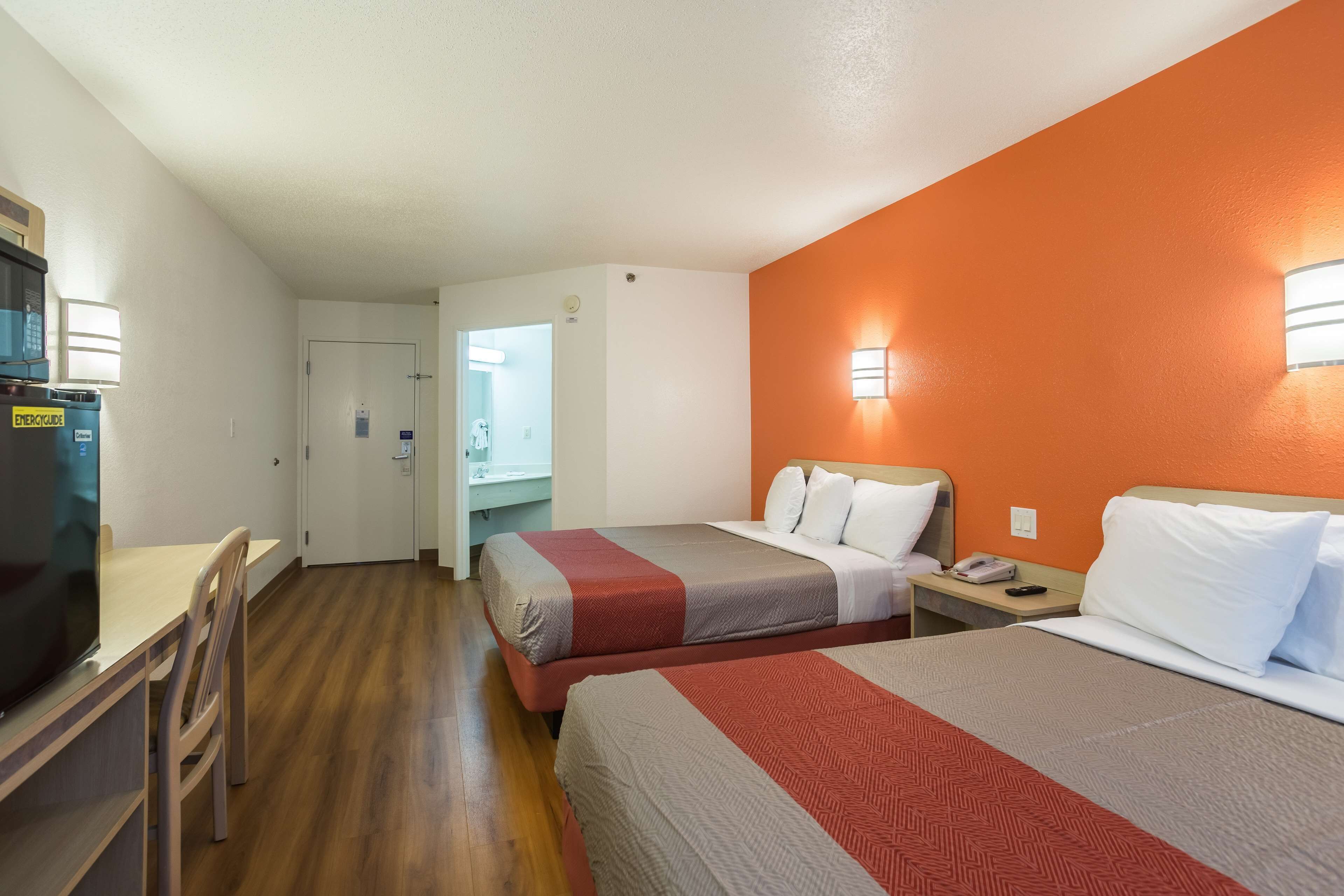 Una habitación de hotel con dos camas, un escritorio, una silla, un microondas y un refrigerador.