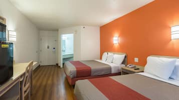 Una habitación de hotel con dos camas, un escritorio, una silla, un microondas y un refrigerador.