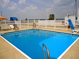 Una piscina rectangular con cerca blanca, un flotador salvavidas y una escalera azul flotante.