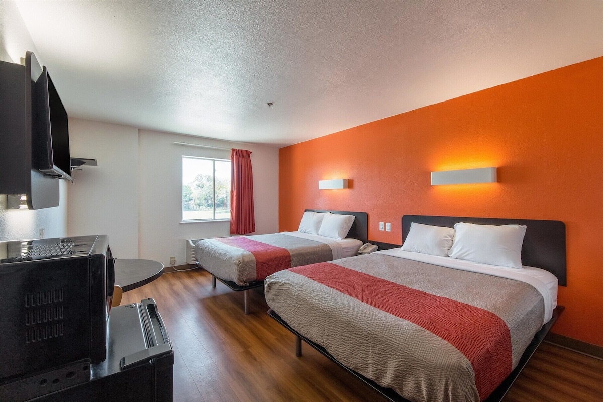 Une chambre d’hôtel avec deux lits, une télévision et un bureau.