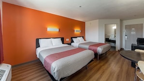 A hotel room with two beds, a desk, and a chair.