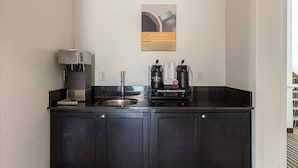 A compact kitchen with a coffee machine, a coffee dispenser, and a coffee station.
