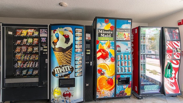 A row of vending machines with various snacks, ice cream, and drinks.