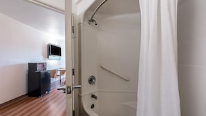 A modern bathroom with a bathtub, a shower curtain, and a handrail.