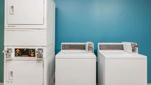 A laundry room with stacked washers and dryers against a teal wall. - Days Inn by Wyndham Vernal (Vernal)