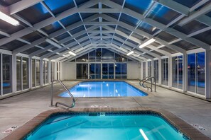 An indoor swimming pool with a high ceiling and glass walls, surrounded by a concrete floor and metal railings. - Days Inn by Wyndham Vernal (Vernal)