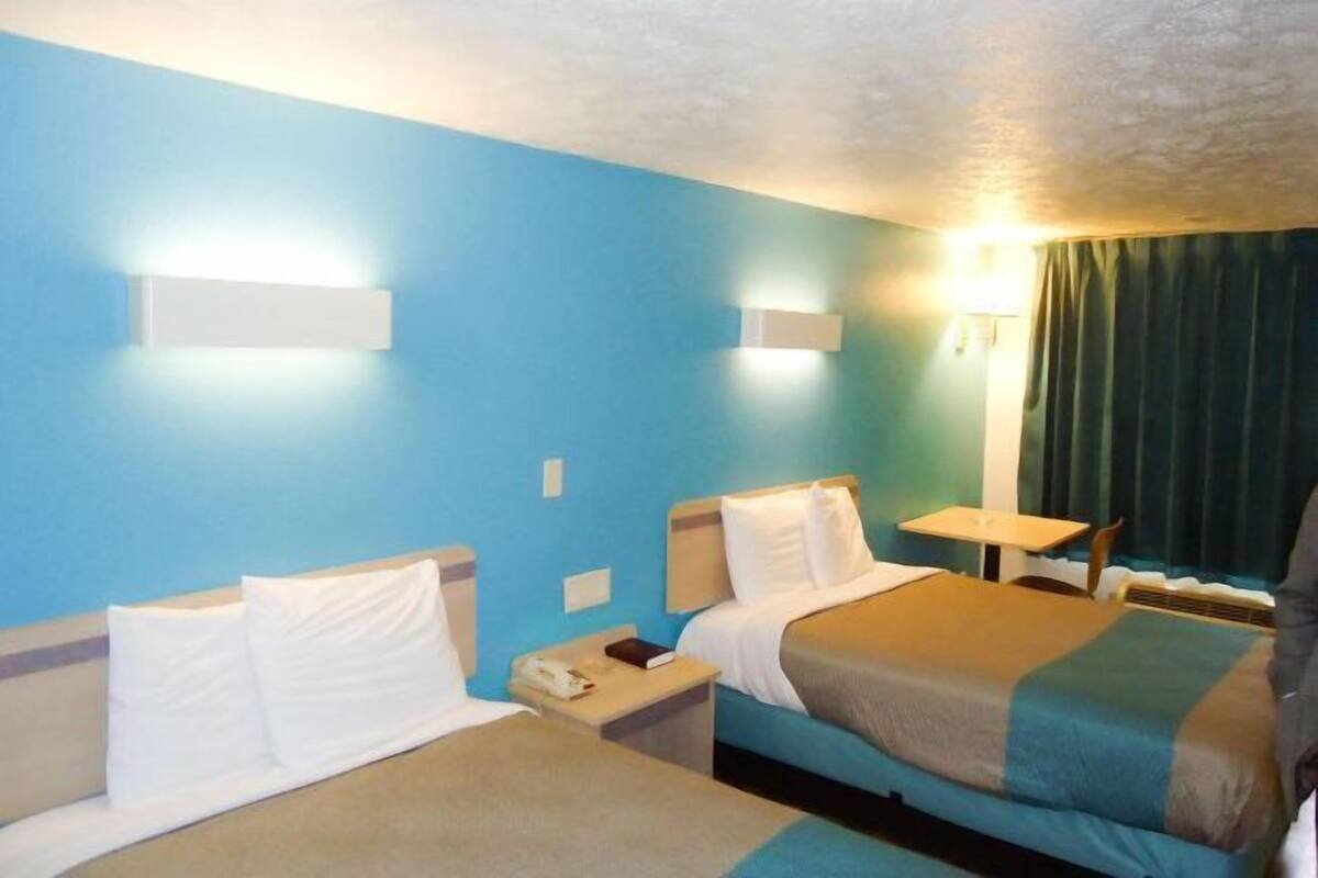 Une chambre d’hôtel avec deux lits, une petite table et une chaise.
