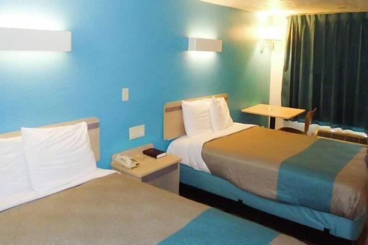 Une chambre d’hôtel avec deux lits, une petite table et une chaise.