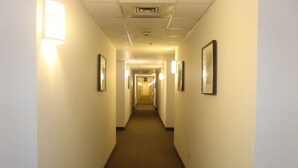 A hotel hallway with a carpeted floor, framed pictures on the walls, and a light fixture on the left. - Howard Johnson by Wyndham Tifton GA I-75 (Tifton)