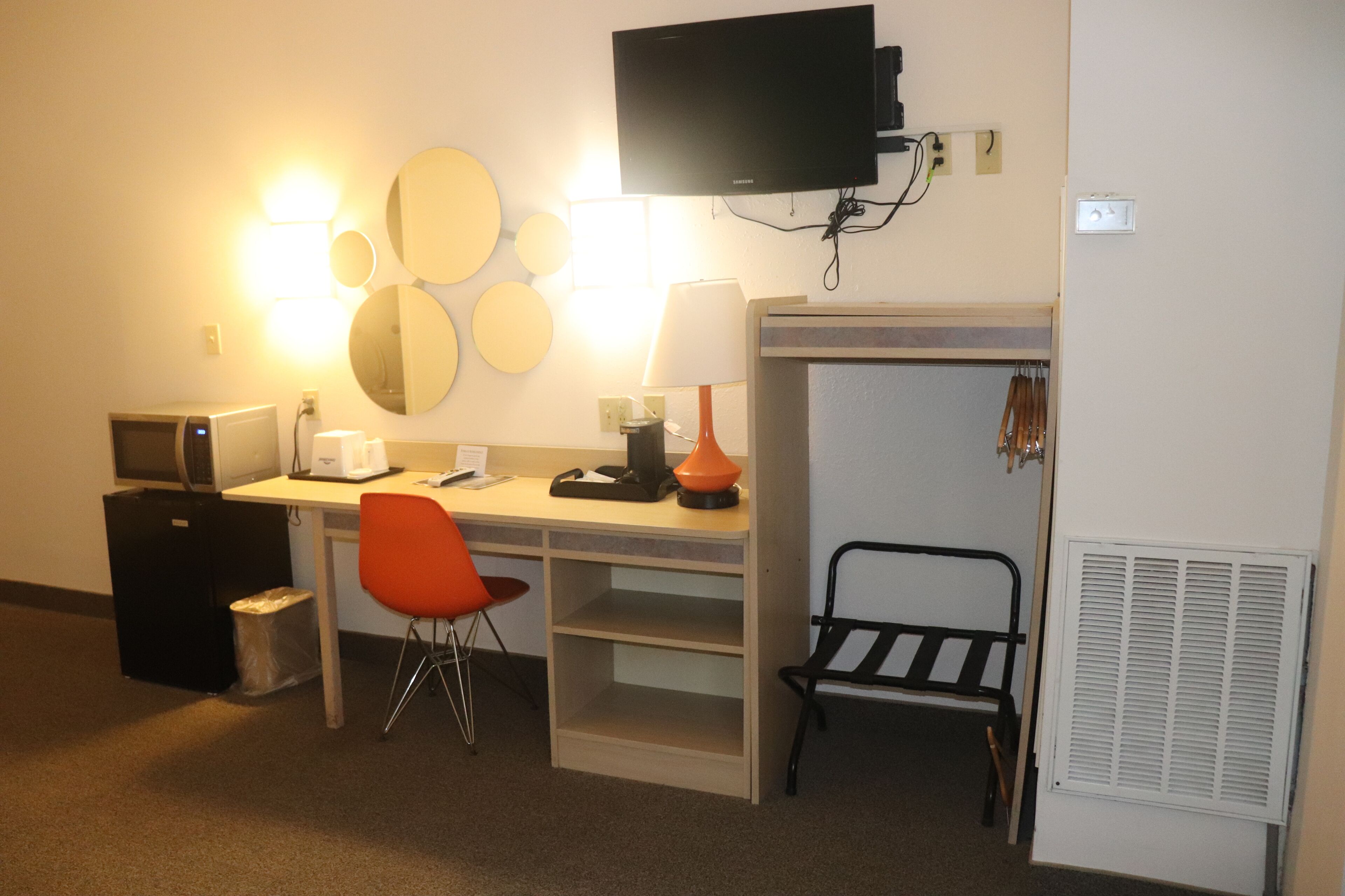 Una habitación de hotel con escritorio, silla, televisor, calentador y basurero.