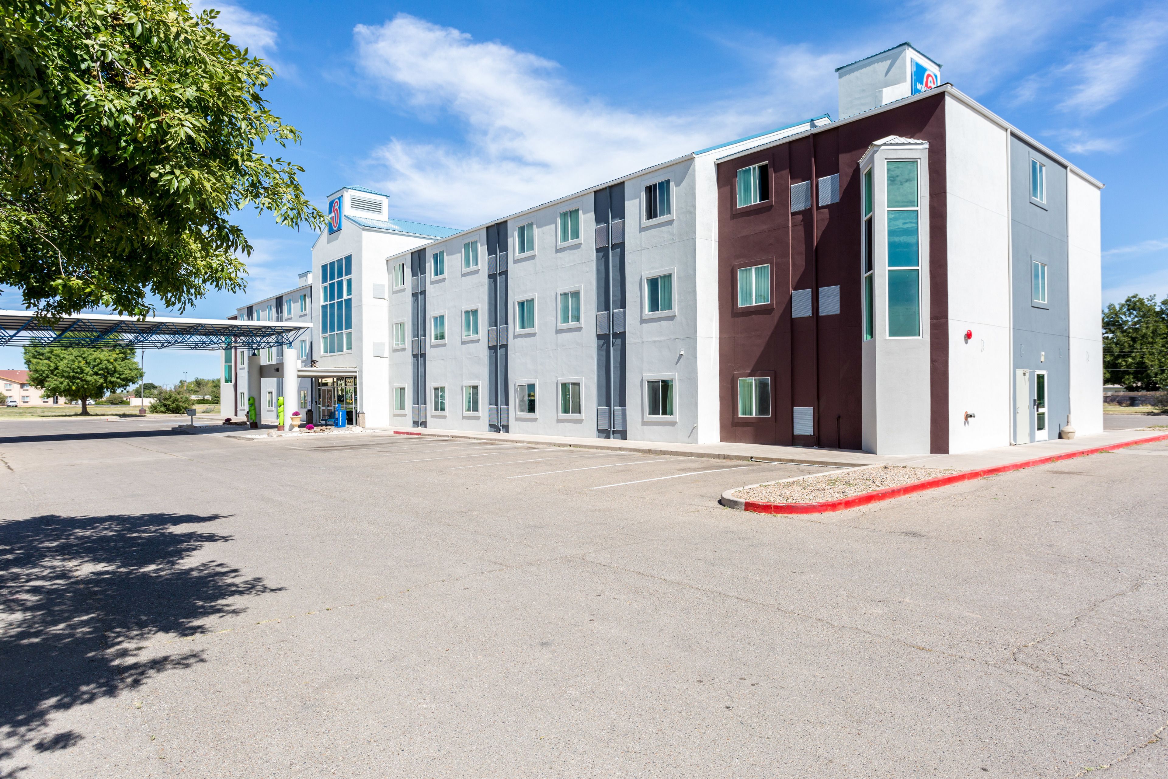 A multi-story hotel with a parking lot and a covered walkway.