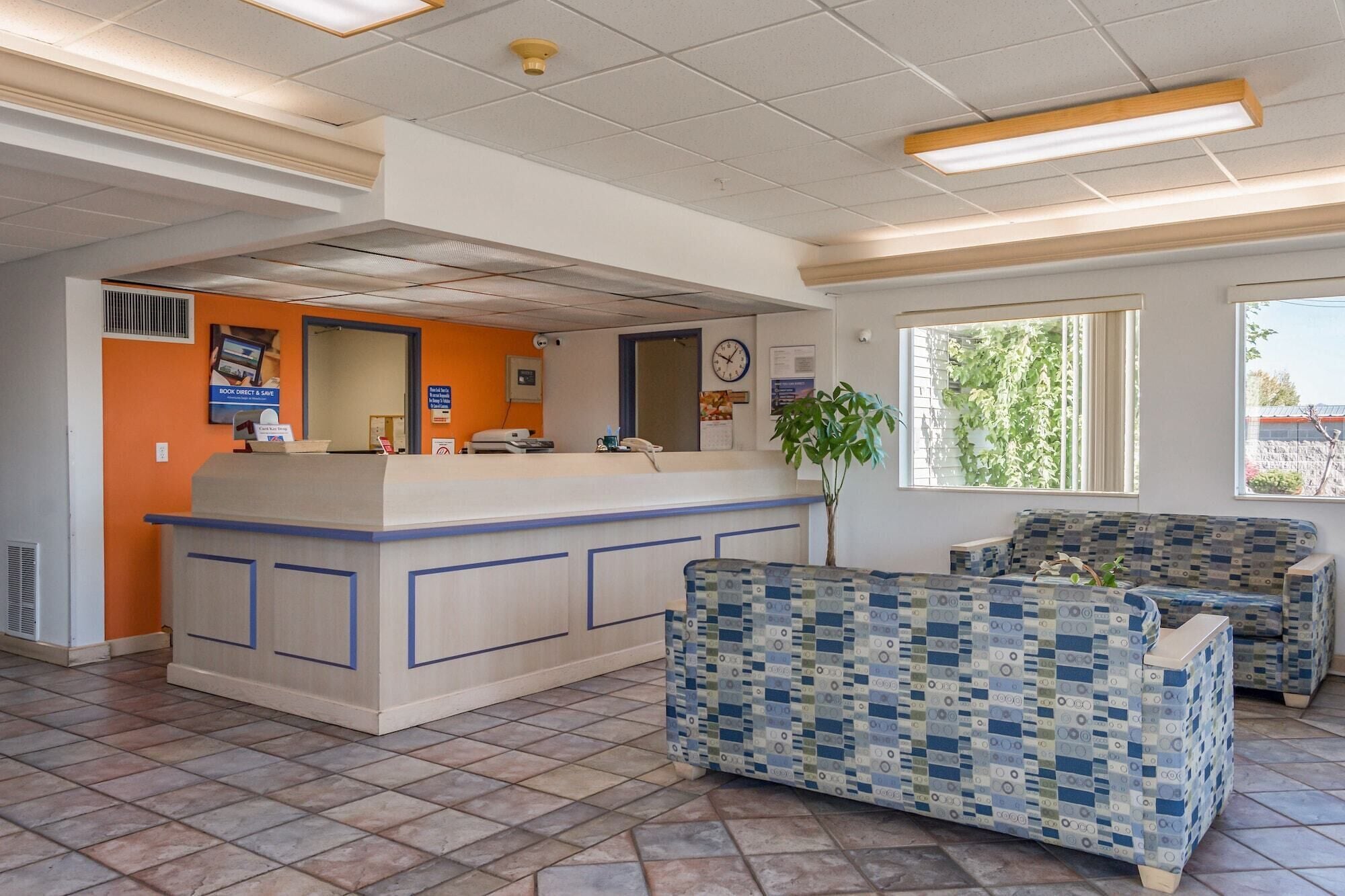 A reception area with a counter, a clock, and a plant.
