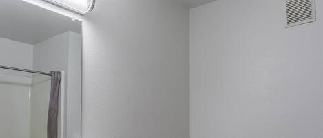 A bathroom with a white sink, mirror, toilet, and handrail.
