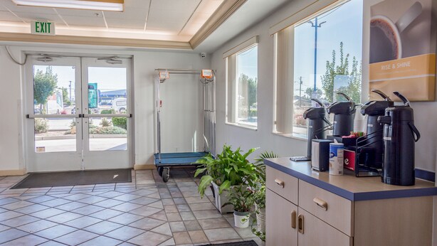 A reception area with a coffee station, a plant, and a view of the outside. - Motel 6 Redmond, OR (Redmond)