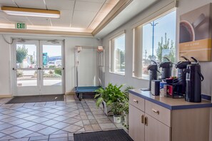 A reception area with a coffee station, a plant, and a view of the outside. - Motel 6 Redmond, OR (Redmond)