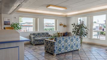 A reception area with two patterned sofas, a reception desk, and large windows offering views of the outside.