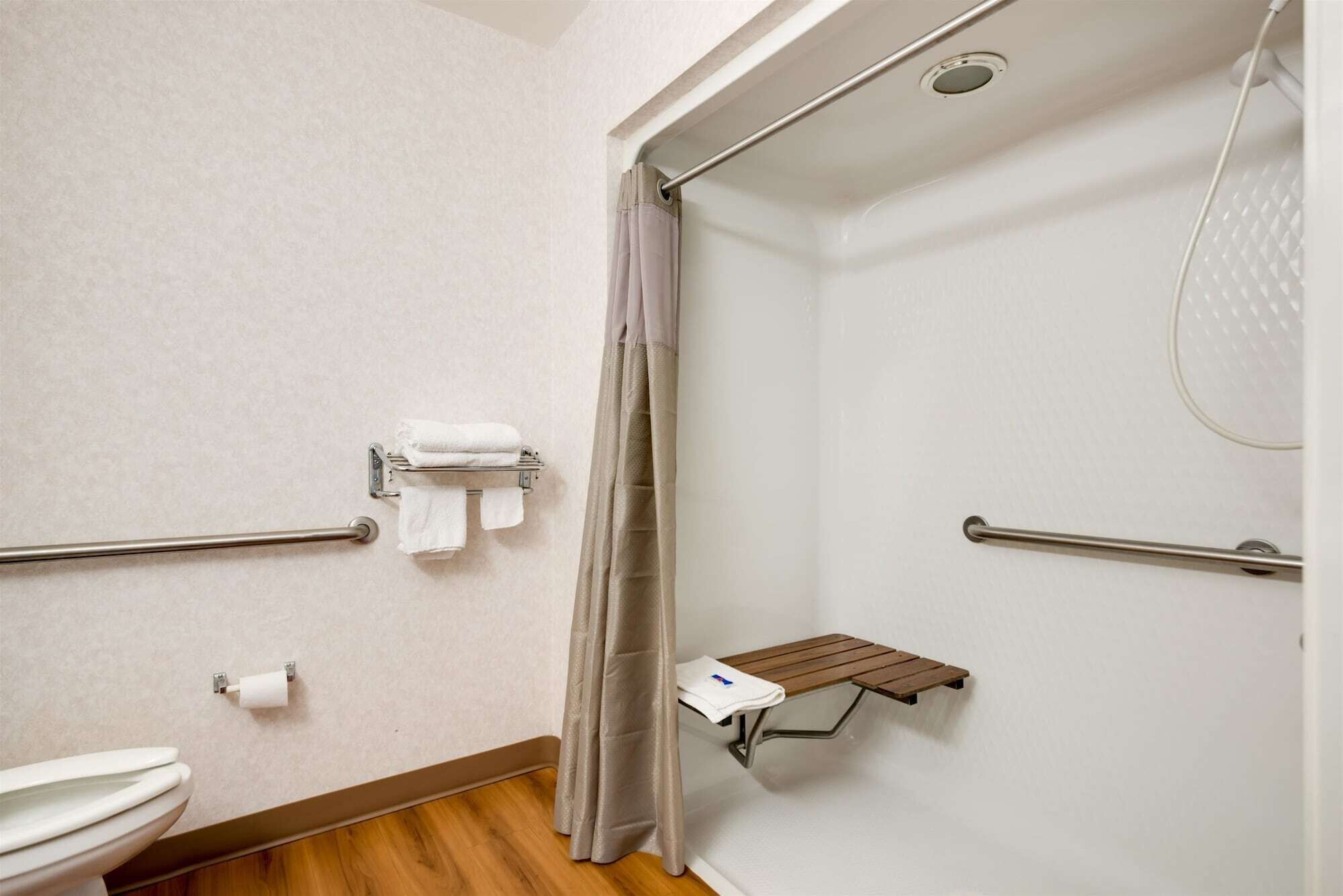 Un baño con ducha, inodoro y perchero para toallas.