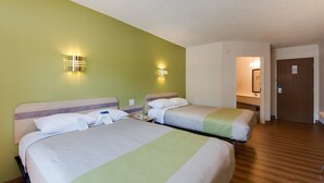 Une chambre d’hôtel avec deux lits, un plancher en bois et une salle de bain visible à travers une porte ouverte.