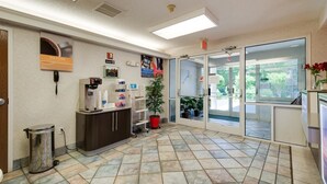 Un espace d’accueil comprenant un bureau, une poubelle, un téléphone, une machine à café et une plante en pot.