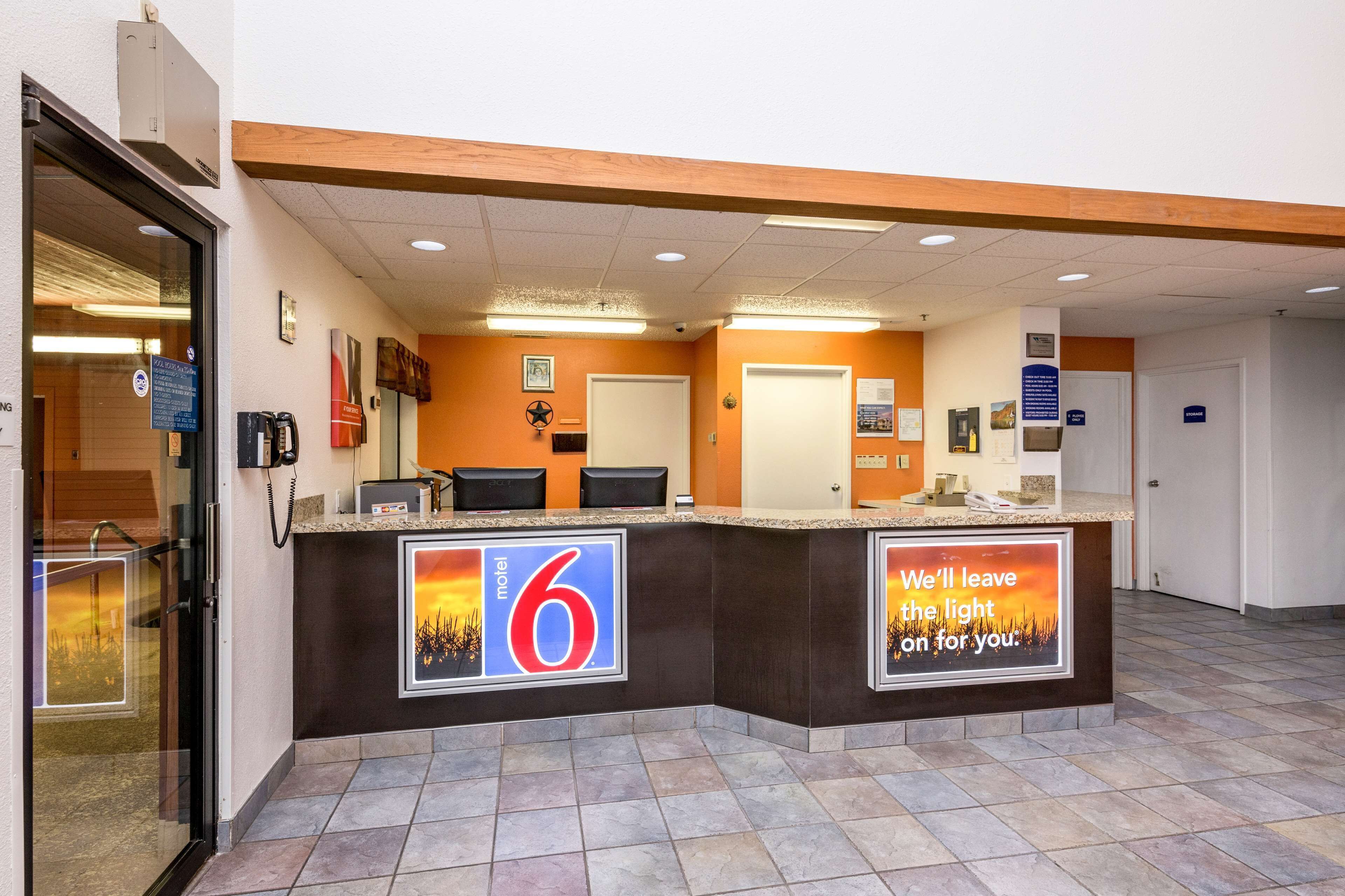 A motel lobby with a reception desk, a sign indicating room number 6, and a message on the wall.