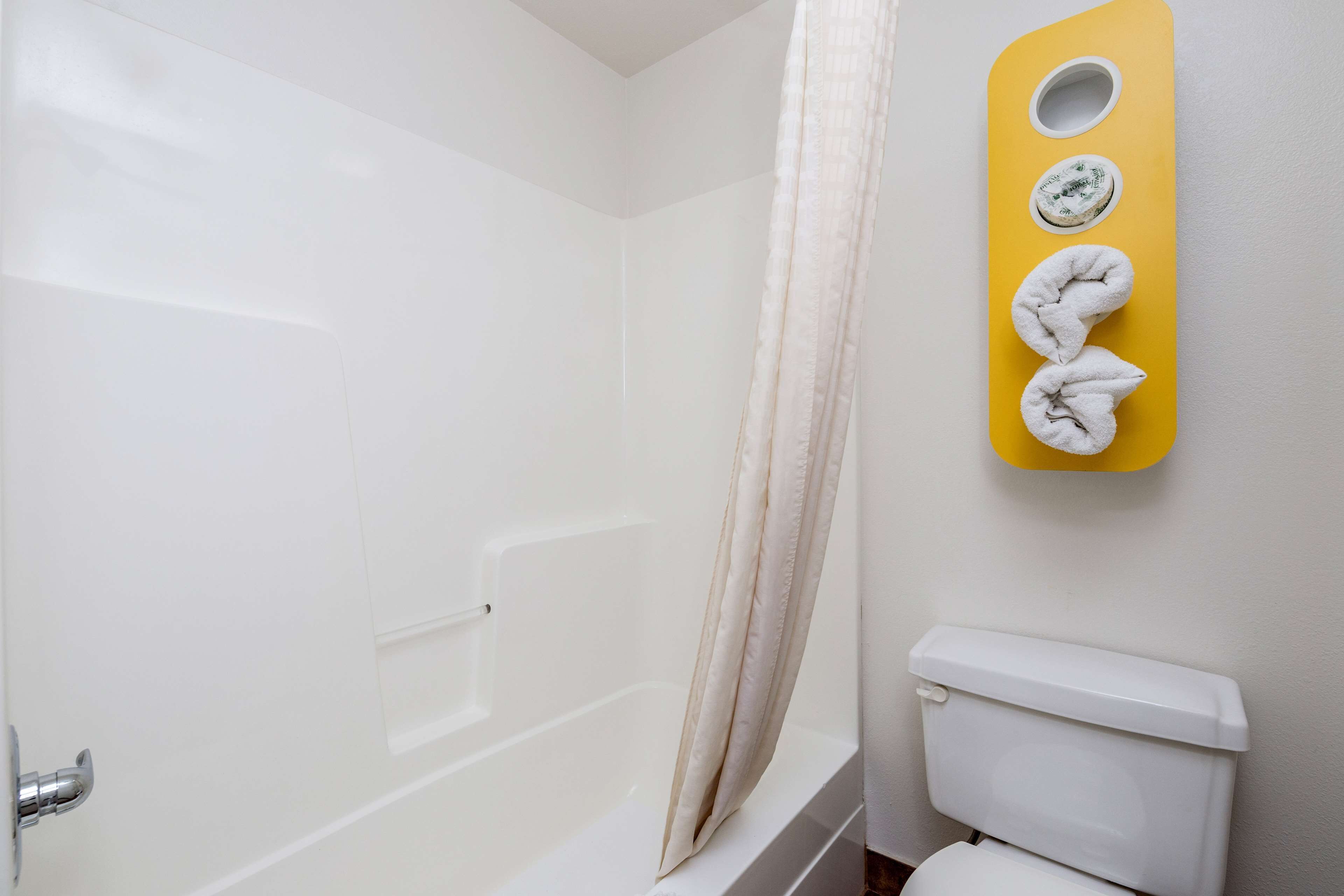 A bathroom with a bathtub, toilet, and a towel rack with towels.