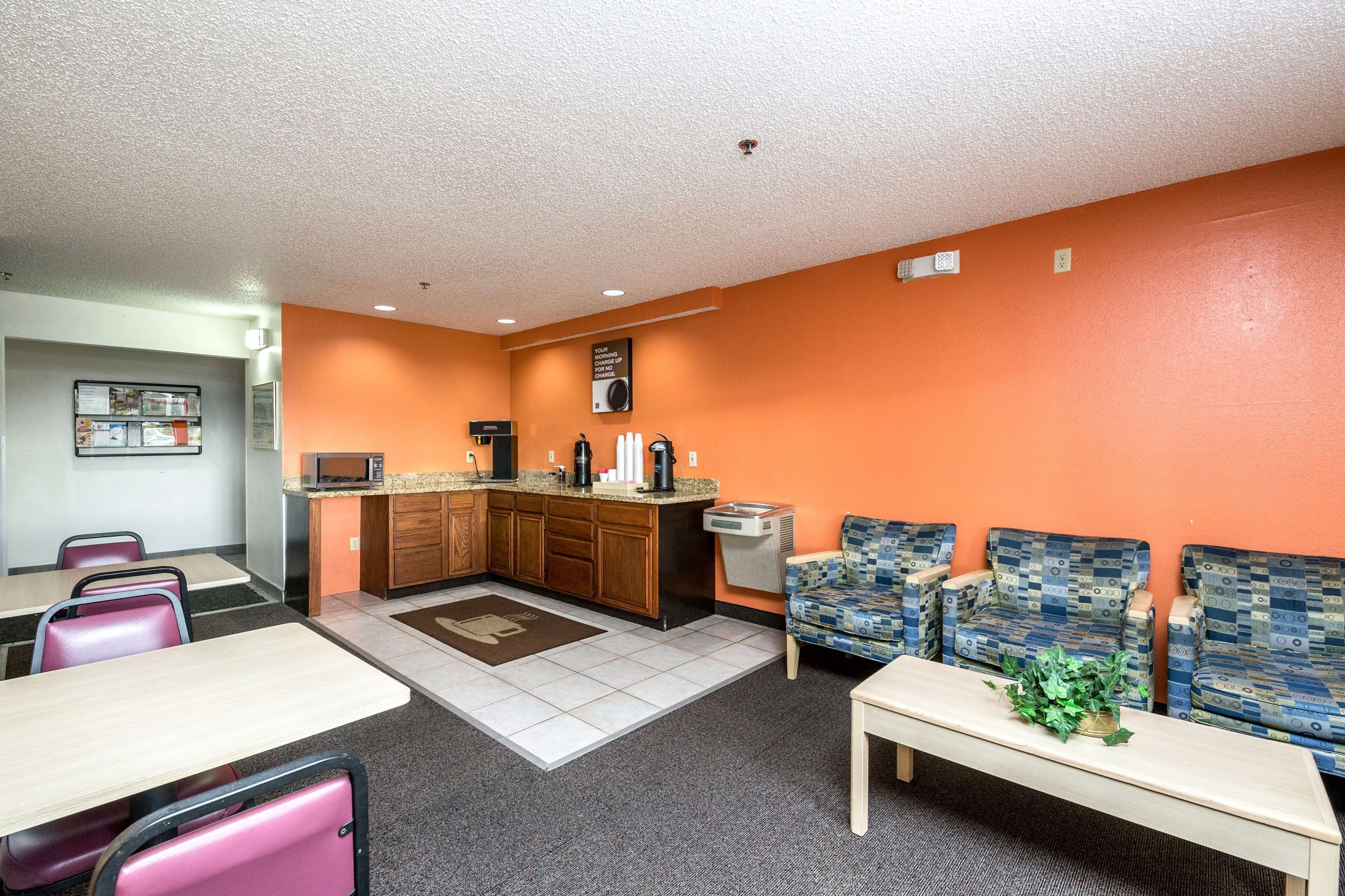 A dining area with tables and chairs, a kitchen with appliances, and a seating area with patterned sofas.