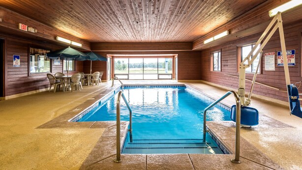 Ein Hallenbad mit Holzvertäfelung, Blick ins Freie und einer Sitzgelegenheit mit Stühlen und Tischen.