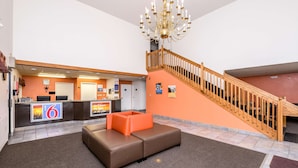 Eine Lobby mit einer Rezeption, einer Treppe und einer Sitzecke.