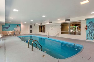 Una piscina interior con una fuente de agua azul, paredes blancas y un mural de criaturas marinas.
