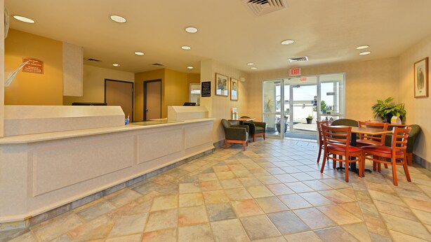A reception area with a reception desk, chairs, a table, and a door leading outside. - Econo Lodge Belle Fourche (Belle Fourche)