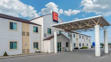 A hotel with a covered entrance, a prominent sign, and a parking lot.