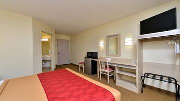 Una habitación de hotel con cama, escritorio, silla y armario.