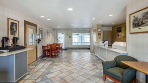A hotel lobby with a reception desk, chairs, a small sofa, tiled flooring, and framed pictures on the walls. - Econo Lodge Belle Fourche (Belle Fourche)