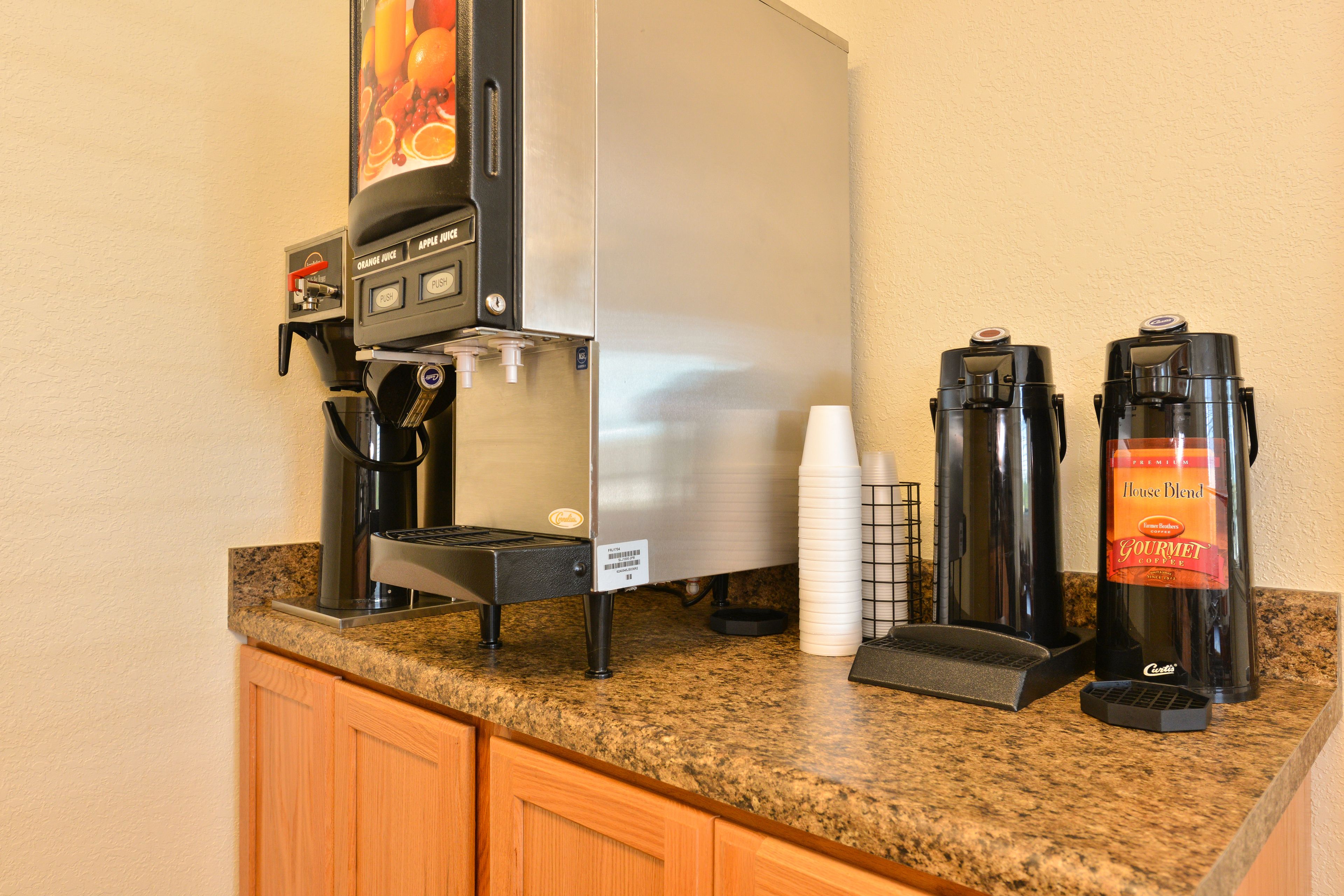 A coffee station with a coffee maker, a water dispenser, and a coffee grinder on a granite countertop.