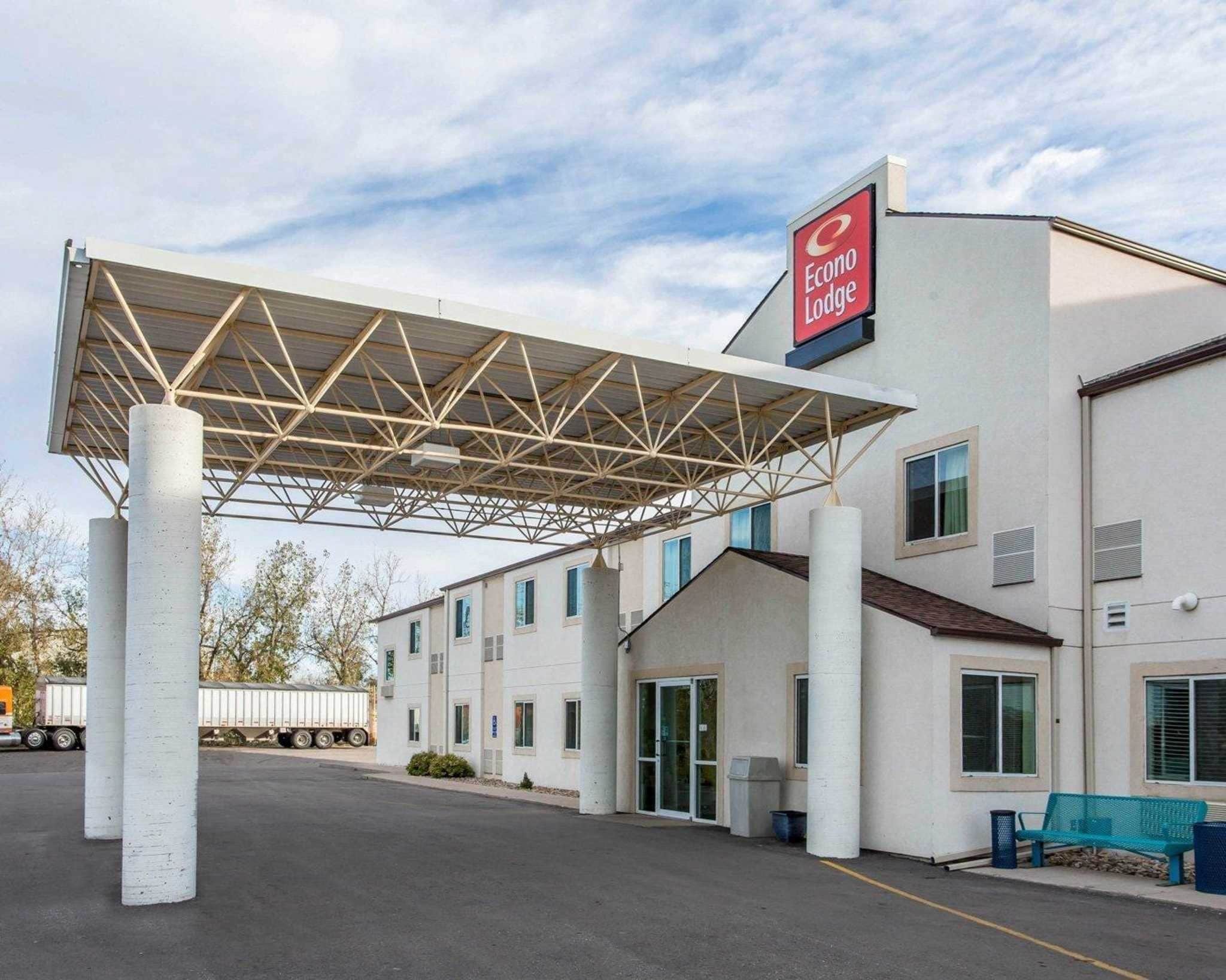 Een hotel met een overdekte parkeerplaats, een bord met Econo Lodge erop, en een vrachtwagen op de achtergrond.