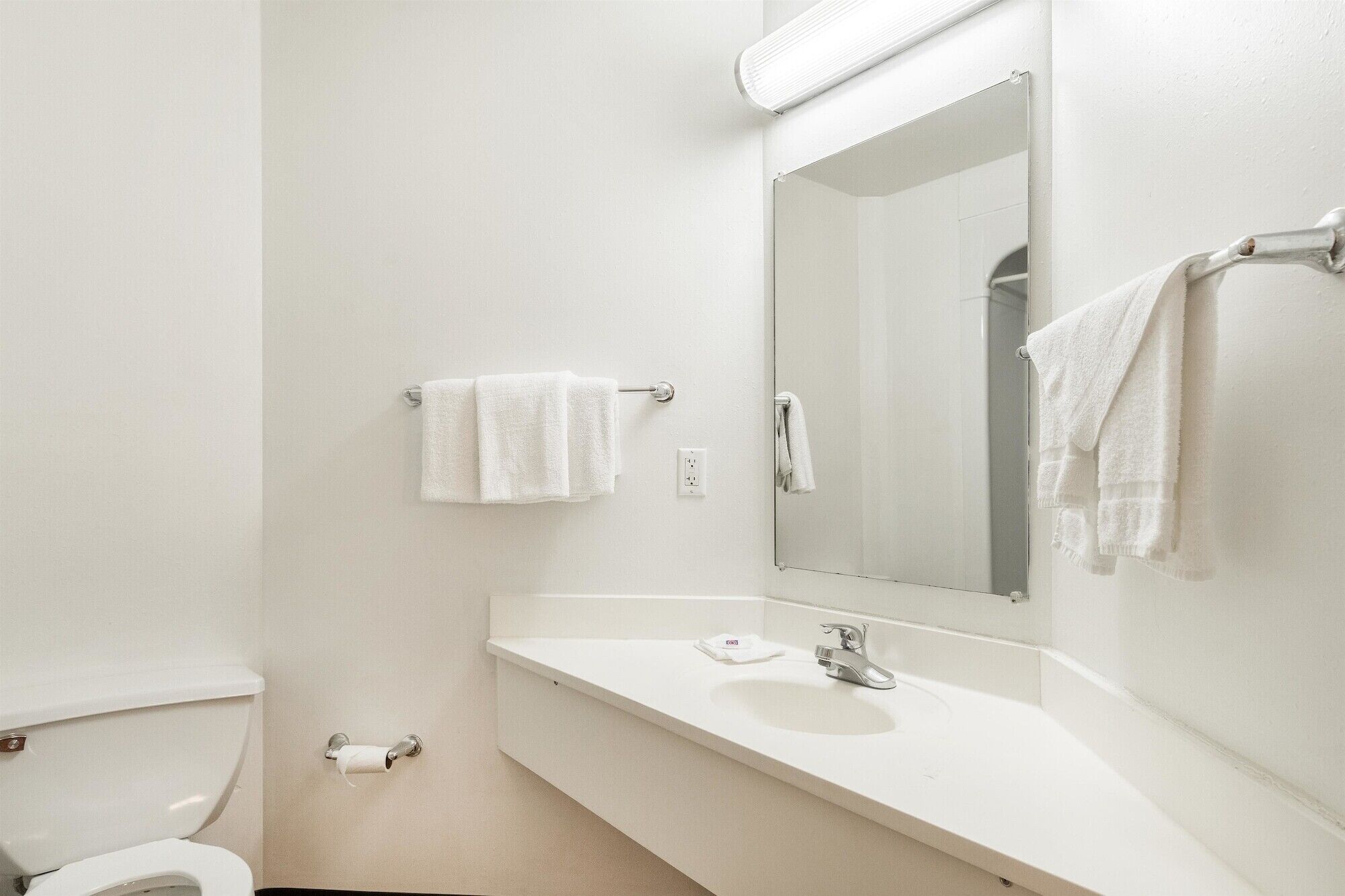 A bathroom with a toilet, sink, and mirror.