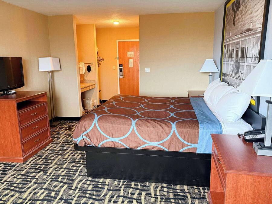 Een hotelkamer met een bed, een televisie, een bureau en een badkamer zichtbaar door een geopende deur.