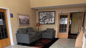Un hall con sillones grises, un cuadro enmarco con una escena desértica, un cartel de Cozad, Nebraska y una lámpara roja.