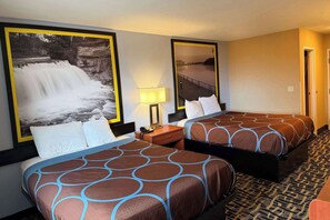 A hotel room with two beds, a nightstand with a lamp, and a large framed picture of a waterfall.