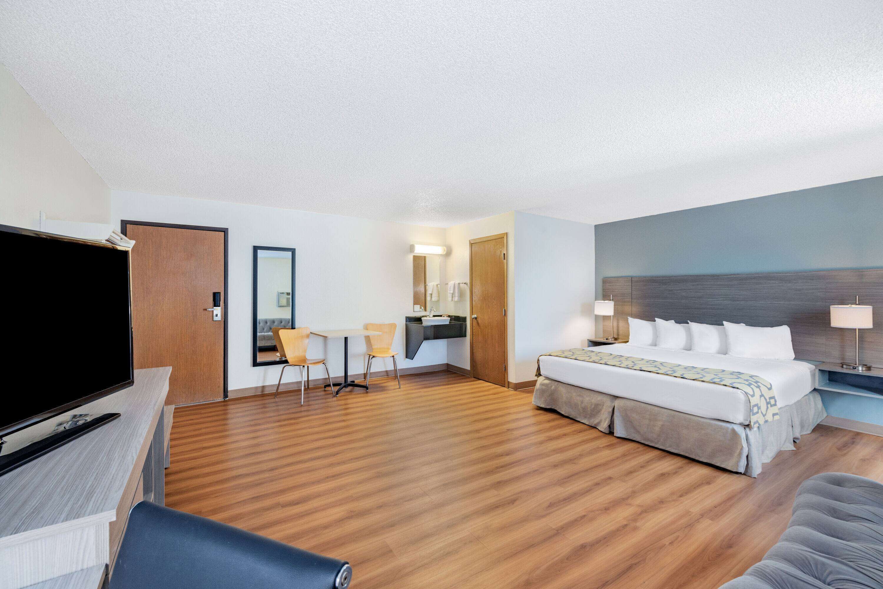 A hotel room with a bed, a desk, a TV, and a bathroom.