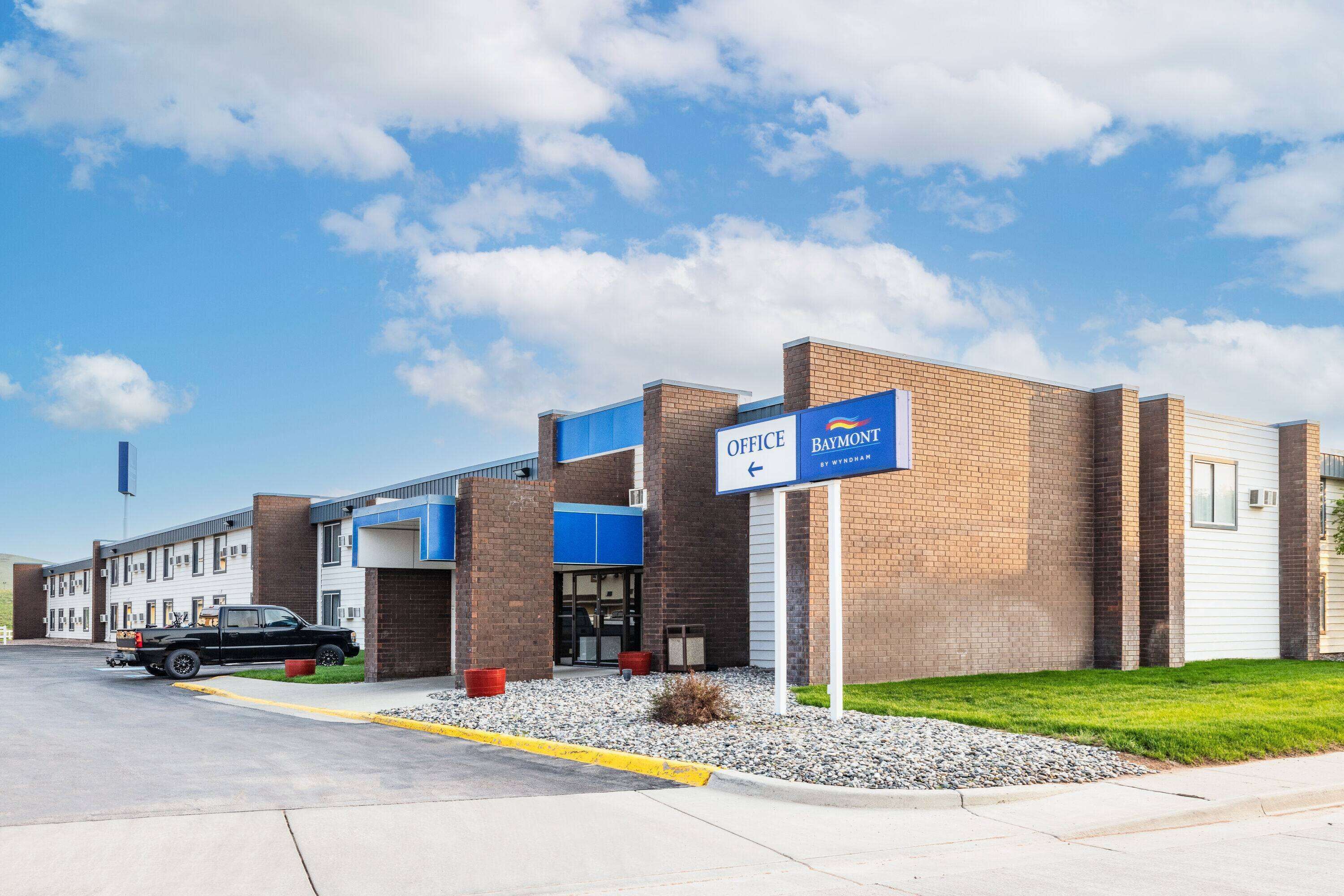 A building with a sign indicating an office and a parking area.