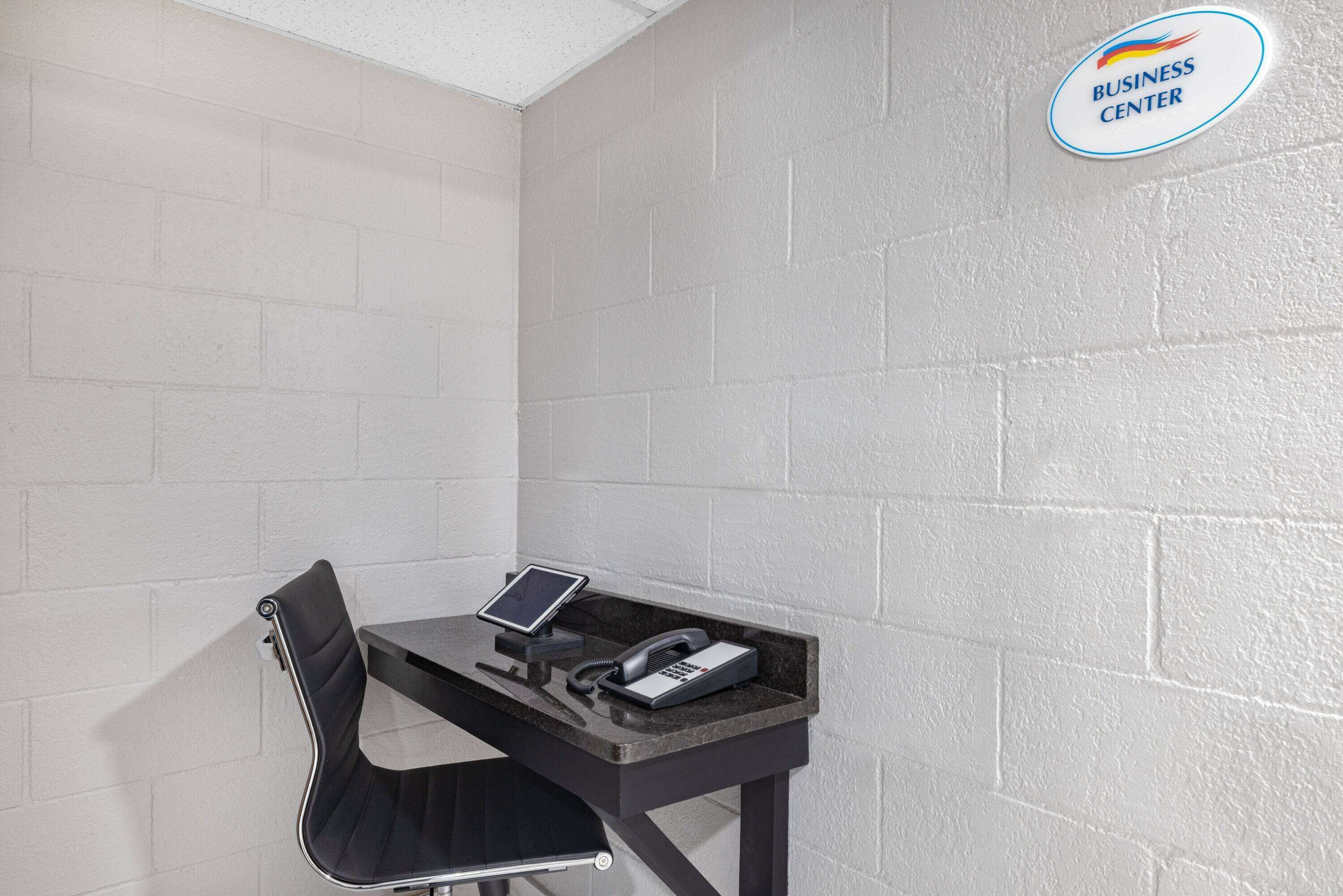 A business center with a desk, chair, phone, and a tablet.