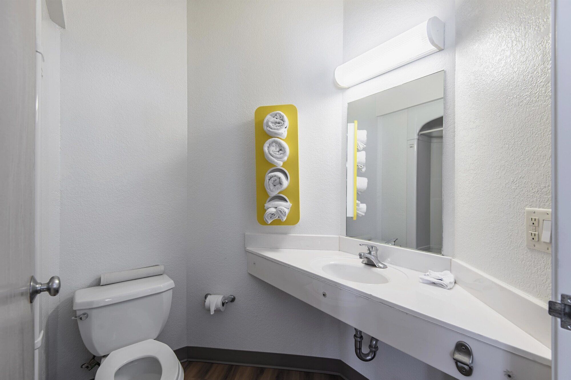 A bathroom with a toilet, sink, mirror, and towel rack.